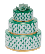 Herend "Wedding Cake" is a three-tiered porcelain box featuring hand-painted green and white patterns, gold edges, and a green flower topper, inspired by the Queen Victoria collection.