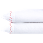Two white John Robshaw Stitched Coral Pillowcase Pairs are stacked, each made of pure cotton percale and featuring a decorative red zigzag stitch along the edge.