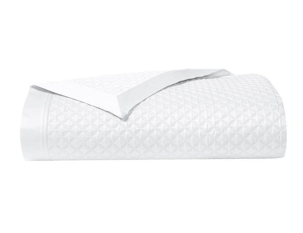 Yves Delorme Adagio Bedding Collection, Blanc quilted blanket with Yves Delorme embroidery, folded on a white background.