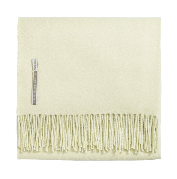 Cream-colored fringed Alicia Adams Alpaca Classic Throw blanket with label.