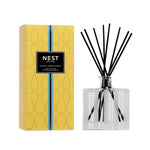 A Nest Amalfi Lemon & Mint Diffuser with black reeds stands beside its yellow patterned box, displaying the product name and details, filling the air with zesty lemon and mint notes.