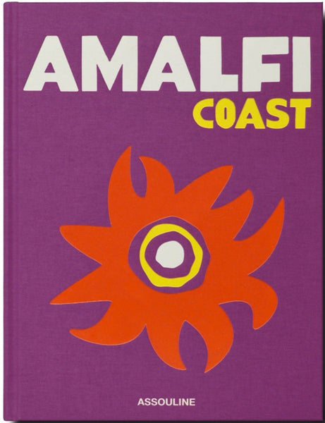 A book with a purple cover titled "Italian Dream: Amalfi Coast" featuring a graphic of a red and yellow sun-like design, with the publisher's name "Assouline" at the