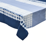 The Kim Seybert Duo Dye Navy/Periwinkle Tablecloth, featuring a wave-inspired design, elegantly drapes over the corner of a rectangular table.