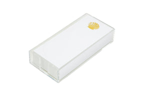 The Black Ink Skinny Lucite Notepad Holder is a high quality rectangular white box with a transparent Lucite tray outer case and a small gold shell emblem on the top right corner.