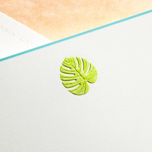 The Printery Palm Leaf Card Set features bright white cards with an embossed green monstera and palm leaf design, shown diagonally on a peach and white background.