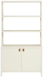 The Jake Bookcase by Made Goods is crafted from White Faux Belgian Linen, featuring three open shelving units and a two-door cabinet with gold handles for ample bottom storage.
