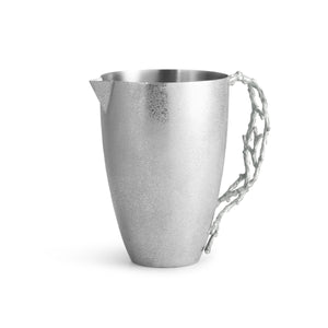 The Ocean Reef Pitcher by Michael Aram features hand-textured stainless steel with a matte finish and a sculpted, branch-like handle, showcasing intricate beauty against a white background.