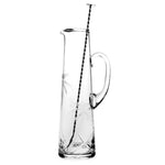 The William Yeoward Crystal Palmyra Tall Cocktail Jug & Spoon is a clear, handmade glass pitcher with a handle, etched palm tree design, and includes a long metal stirring spoon—an elegant addition to any table.