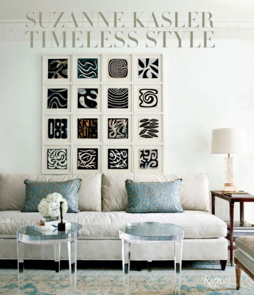 A living room featuring a beige sofa, two round glass tables, and abstract black and white art in square frames exudes the timeless style of Suzanne Kasler. Rizzoli's "Suzanne Kasler: Timeless Style" highlights her haute couture details, showcasing her interior design mastery.
