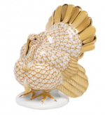 The Herend Tom Turkey Collection features a handmade porcelain turkey figurine with 24K gold accents and white scale-patterned feathers, standing elegantly on a white base.