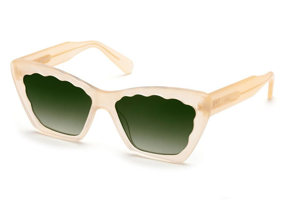 A pair of Krewe Brigitte sunglasses with beige frames and green-tinted lenses, featuring 100% UVA/UVB protection, on a white background.