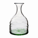 The Green Vanessa Carafe by William Yeoward Crystal features handmade glass with a wide base, narrow neck, spiral design, and Mediterranean-inspired green speckles at the bottom. Displayed on a plain white background.
