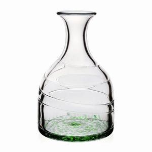 The Green Vanessa Carafe by William Yeoward Crystal features handmade glass with a wide base, narrow neck, spiral design, and Mediterranean-inspired green speckles at the bottom. Displayed on a plain white background.