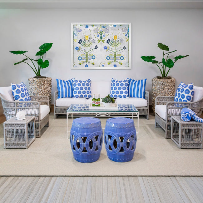 outdoor seating arrangement with gray woven sofa with white cushions and blue pillows
