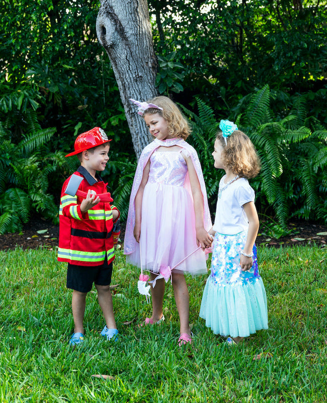 three children standing in grass wearing Halloween costumes