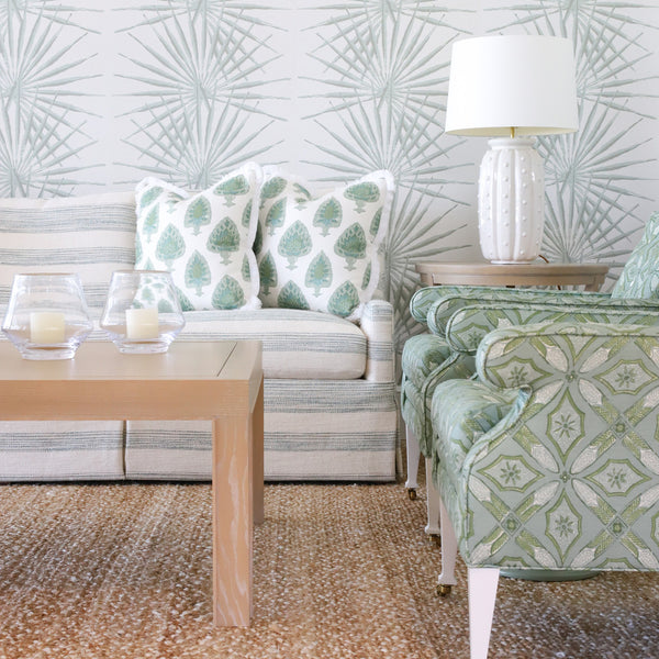 Living room with seafoam chairs, wallpaper, and sofa, with natural woven rug