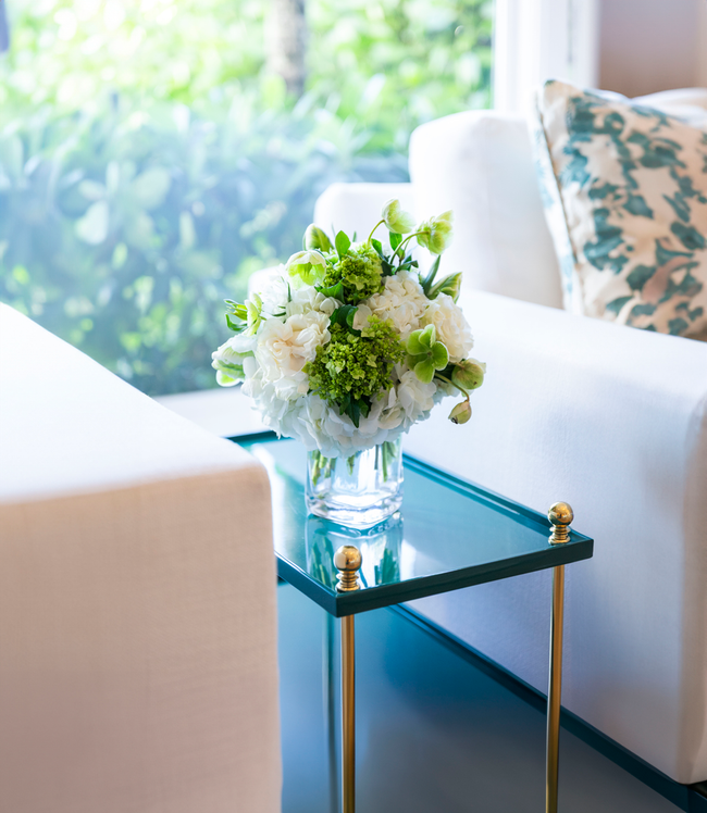 white and green floral arrangement sitting on a side table