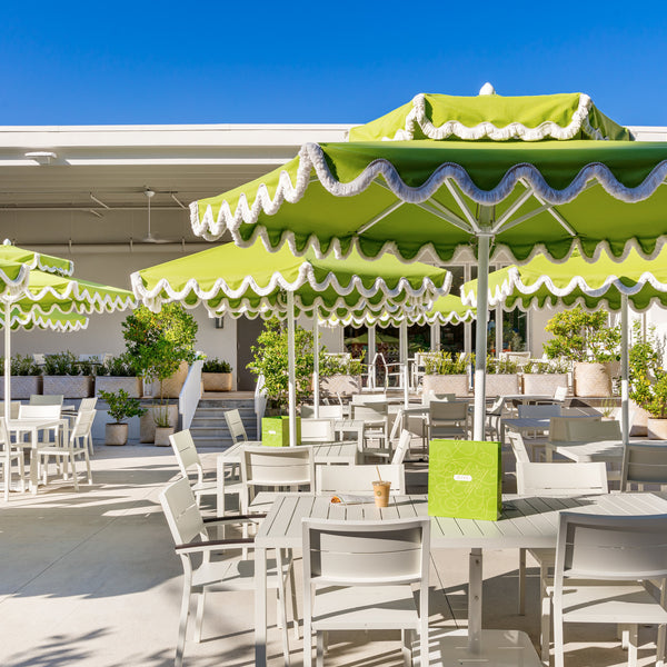 Outdoor dining at hive with white tables and green umbrellas