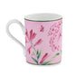 A white ceramic mug from the Florenza Impero Malva Dinnerware and Decor Collection by Ginori 1735, featuring floral and butterfly designs in pink and green on a pink background, inspired by timeless Tuscany tableware.