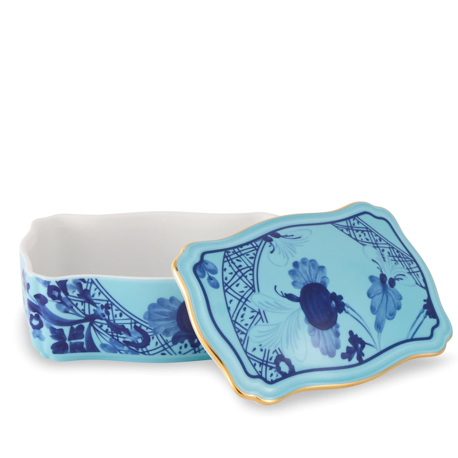 Ginori 1735’s Oriente Italiano Iris with Gold Dinnerware & Decor Collection features a rectangular blue porcelain box adorned with floral designs and elegant gold trim, reminiscent of fine porcelain dinnerware, displayed with its matching lid resting askew beside it on a white background.