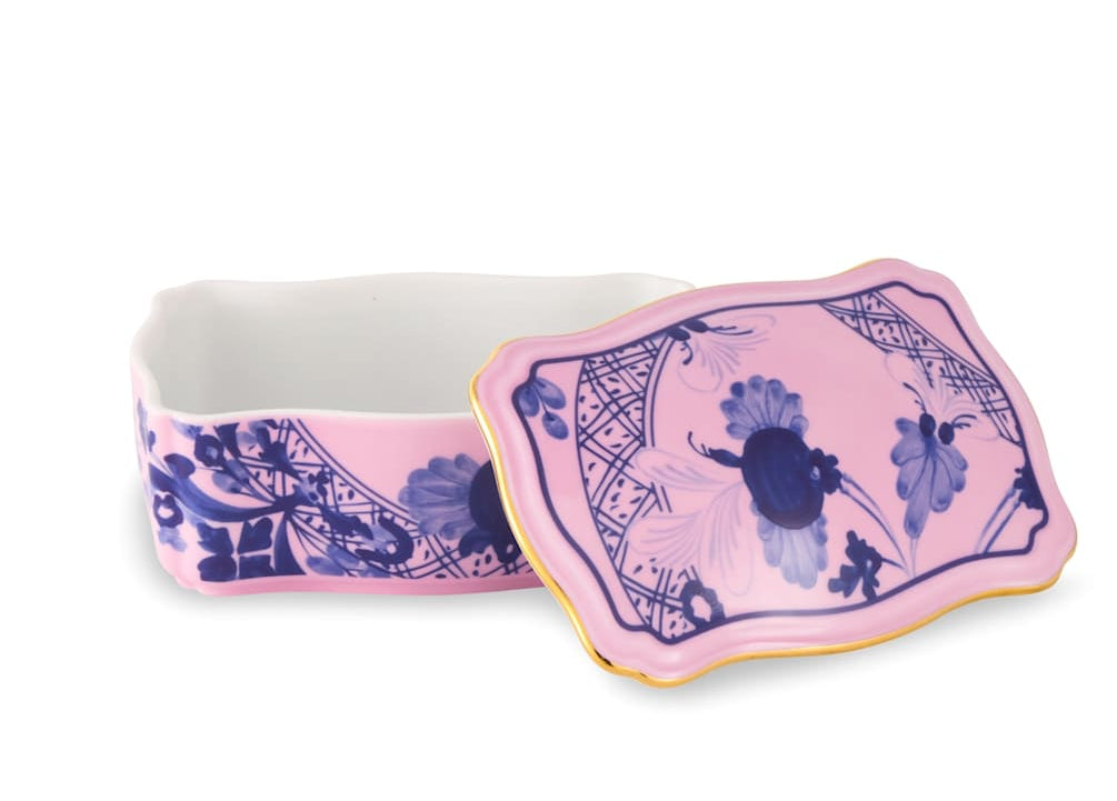 The Oriente Italiano Azalea Serveware & Decor Collection by Ginori 1735 features a rectangular porcelain box with a matching lid, pink background, blue floral patterns, gold trim, and white interior—an elegant addition to any home decor.