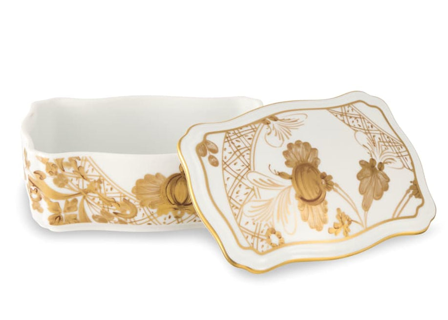 The Ginori 1735 Oriente Italiano Aurum Decor Collection features a rectangular white porcelain box with gold floral patterns and a matching removable lid, offering a timeless accent for elegant home decor.