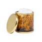A cylindrical tortoiseshell container from the Benton Tortoise Bath Collection by Pigeon & Poodle holds a white cream or mousse, its gold lid resting to the side—an elegant accent for any bath design.