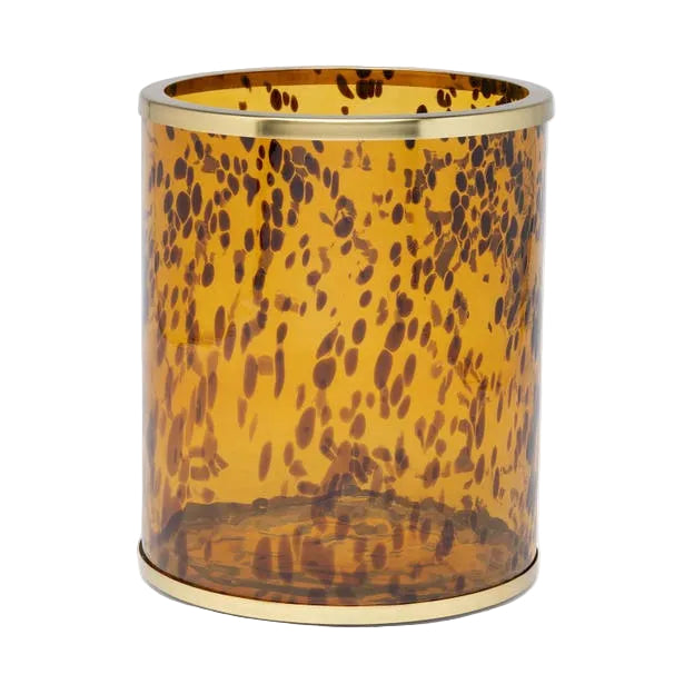 The Benton Tortoise Bath Collection by Pigeon & Poodle features a cylindrical amber glass container with a dark brown mottled pattern and gold-toned rims, adding sophisticated charm to your bath décor.