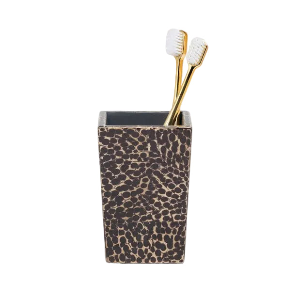 A rectangular, patterned toothbrush holder from Pigeon & Poodle’s Callas Bath Collection features elegant mosaic detailing and holds two gold-handled toothbrushes with white bristles.