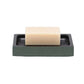 A beige rectangular soap from the Manchester Bath Collection by Pigeon & Poodle sits on a black soap dish with a green shagreen-textured base against a plain white background.