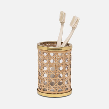 A cylindrical woven rattan toothbrush holder from the Norwell Bath Collection by Pigeon & Poodle, featuring gold accents, holds two beige toothbrushes against a plain white background.