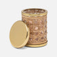 A cylindrical container from the Norwell Bath Collection by Pigeon & Poodle, featuring elegant silhouettes, a woven rattan design, gold metal rims on top and bottom, and a matching gold lid placed beside it.