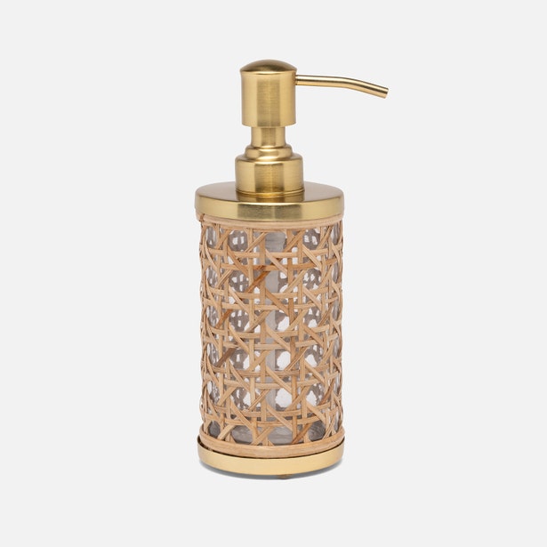 The Norwell Bath Collection by Pigeon & Poodle features a gold and glass soap dispenser with a woven rattan cover, elegant silhouettes, and a pump top, shown against a plain white background.