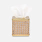 The Pigeon & Poodle Norwell Bath Collection features a woven rattan tissue box with elegant lines and a gold metal top, displaying white tissues through its opening.