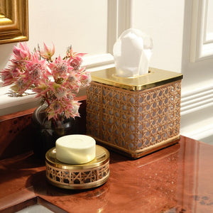A tissue box, soap dish with bar soap, and vase with pink flowers from the Pigeon & Poodle Norwell Bath Collection sit on a polished marble countertop by a white wall with gold trim, highlighting their sophisticated silhouettes.