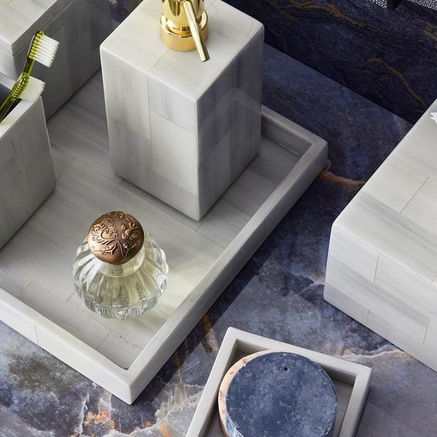 The Arles Bath Collection by Pigeon & Poodle features a sleek marble tray that stylishly displays a gold soap dispenser, glass jar, two toothbrushes, and a round coaster, elevating your bathroom on any dark marble countertop.