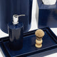 A soap dispenser, shaving brush with wooden handle, and tissue box from Pigeon & Poodle’s Cordoba Navy Bath Collection are arranged on matching hand-textured navy trays.
