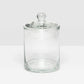The Darby Clear Canister Collection by Pigeon & Poodle features an empty glass container with a round lid and knob, shown on a white surface—perfect as versatile storage or a chic bathroom organizer.