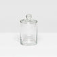 The Darby Clear Canister Collection by Pigeon & Poodle features a clear glass container with a round lid and knob, ideal as a bathroom organizer or for versatile storage throughout your home.