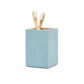 A blue, shagreen-textured square toothbrush holder from the Manchester Bath Collection by Pigeon & Poodle holds two wooden toothbrushes with white bristles, set against a white background.