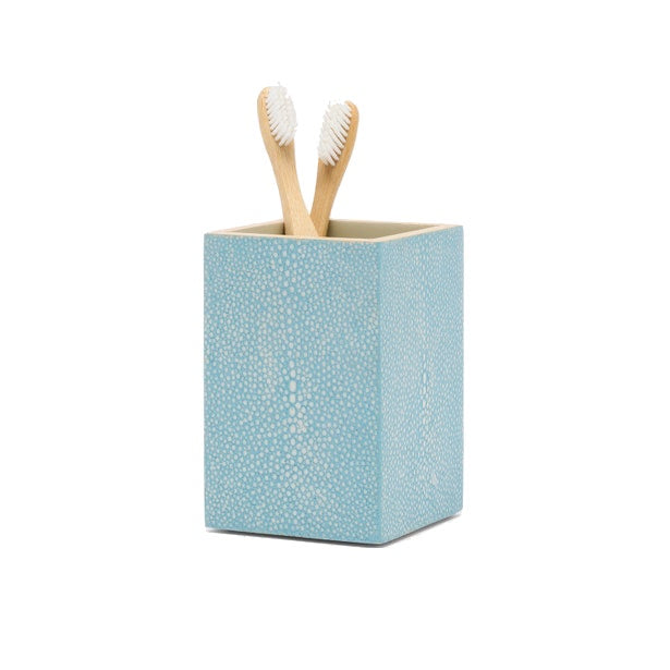 A blue, shagreen-textured square toothbrush holder from the Manchester Bath Collection by Pigeon & Poodle holds two wooden toothbrushes with white bristles, set against a white background.