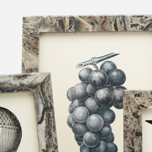 Two Corsica Frames by Pigeon & Poodle, featuring a gray marble design, partially overlap to showcase black and white art of grapes and a hot air balloon.