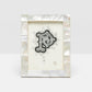 The Lesina Frame Collection by Pigeon & Poodle showcases a decorative black and white letter "P" on white paper in a white kabibe shell frame with mother-of-pearl border, ideal for bringing coastal elegance to your décor.