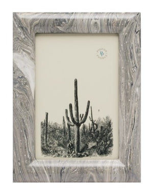 The Gray Swirled Ashland Frame by Pigeon & Poodle, sized 4 x 6, features hand-painted lacquered resin with a marbled gray finish and displays a black-and-white illustration of tall cacti in a desert landscape.