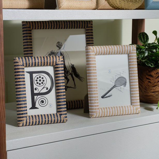 Three framed pictures on a shelf: one with a decorative letter "P" in a Toluca Frame Collection piece, one with a tennis racket sketch, and one in a Pigeon & Poodle striped raffia frame featuring a black-and-white horseback illustration.