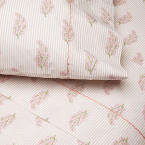 The Nirvi Lotus Bedding Collection by John Robshaw features pink and white bedding with subtle stripes, a pink and green floral block print, quilted details, and a coordinating pillowcase.
