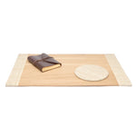 The Pigeon & Poodle Koba Bagor Grass Desk Blotter with Mouse Pad sits atop a rectangular wooden tray with woven edges, evoking 70s style, alongside a brown leather-bound notebook—all set against a white background.