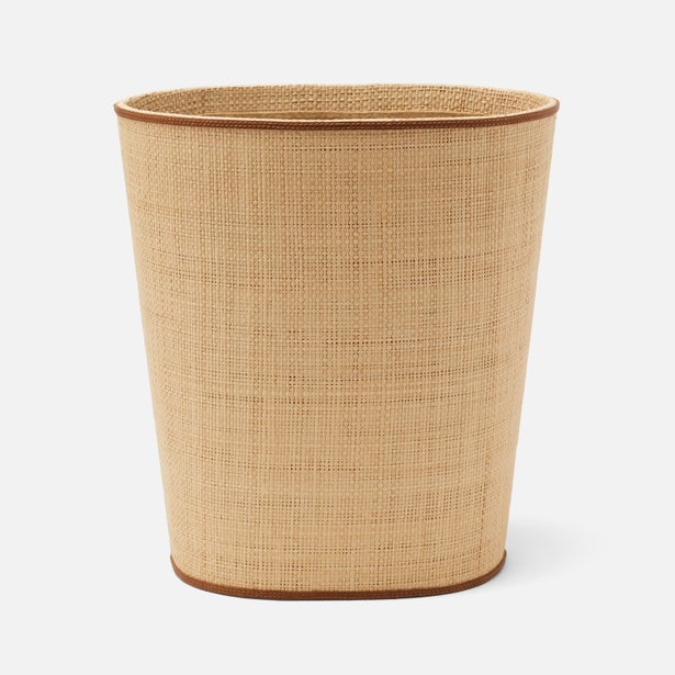 A beige woven wastebasket from Pigeon & Poodle’s Hanford Desk Accessory Collection, featuring raffia and leather details with brown trim accents, is shown against a plain white background.