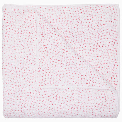 A folded white coverlet from the Hand-Stitched Bedding Collection by John Robshaw, crafted from soft organic cotton and featuring a subtle pattern of evenly spaced small red stitches, is displayed on a plain background.
