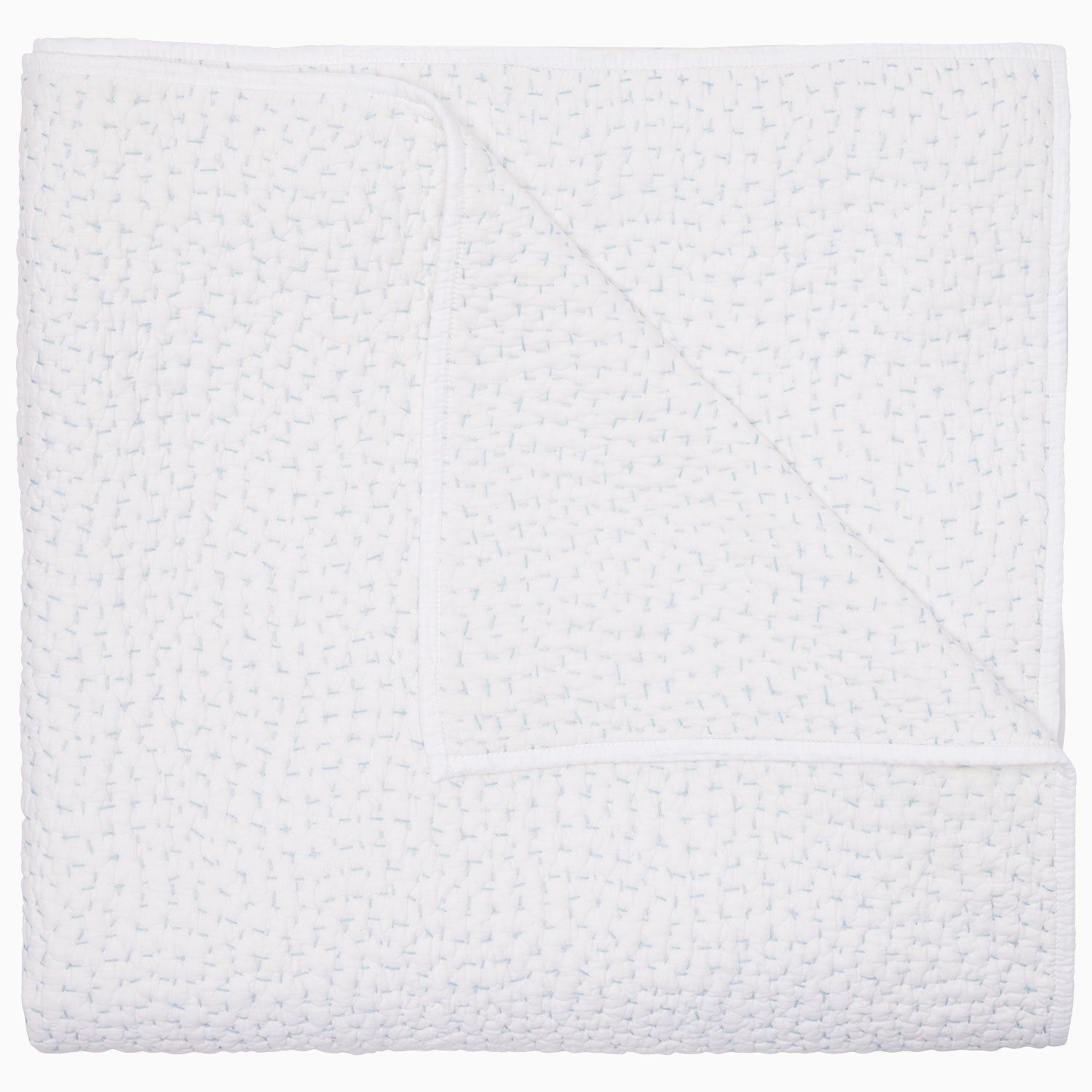 A white, textured coverlet from the John Robshaw Hand-Stitched Bedding Collection, neatly folded with one corner turned down to reveal its soft organic cotton underside.